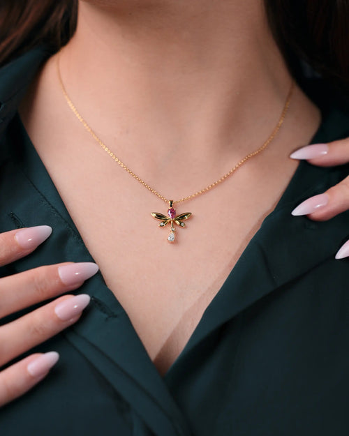 Gold necklace with a butterfly pendant worn by a person, close-up of the necklace.