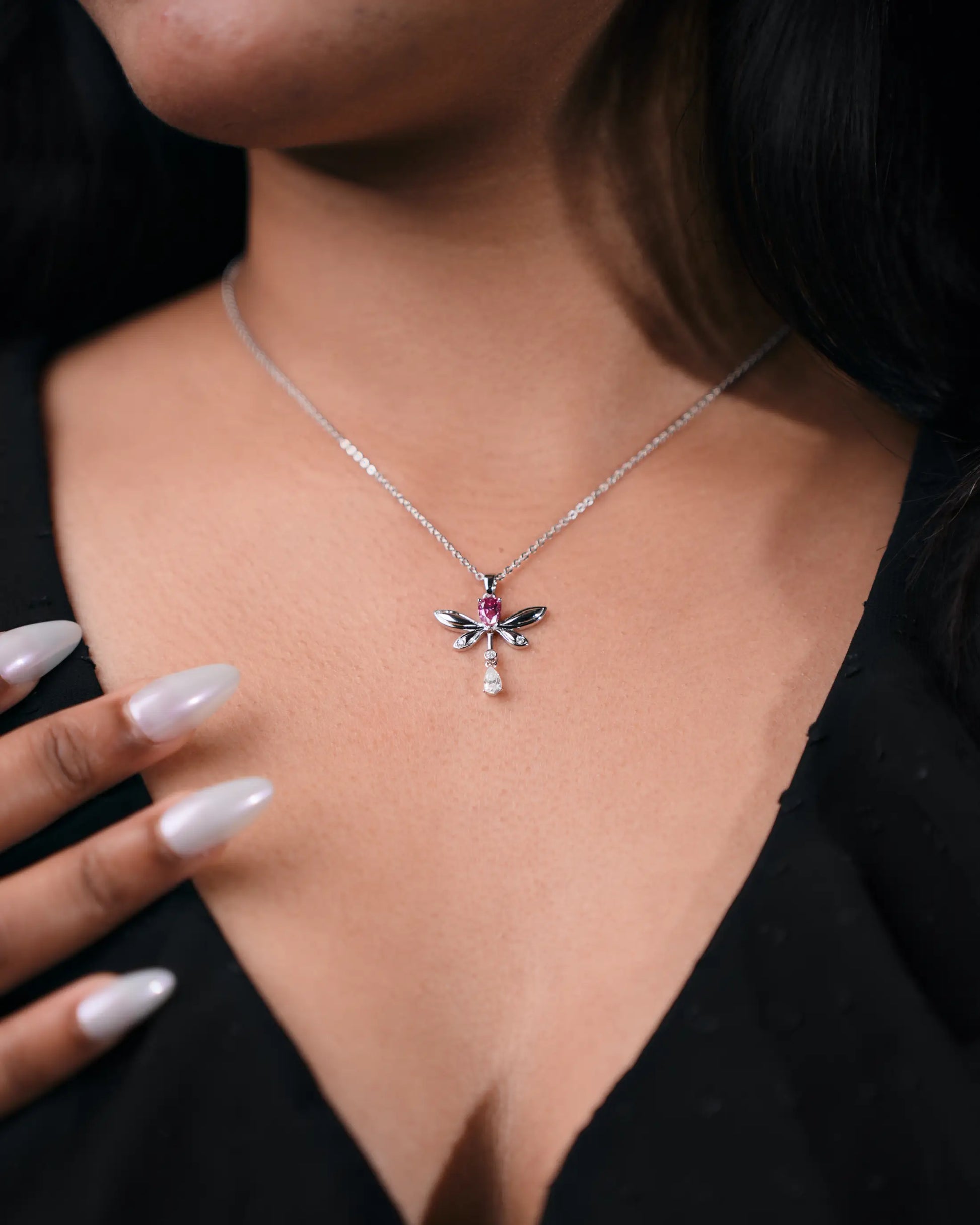 Close-up of a necklace with a dragonfly pendant worn by a person.