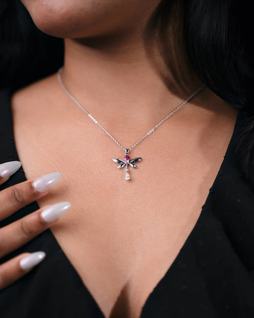 Close-up of a necklace with a dragonfly pendant worn by a person.